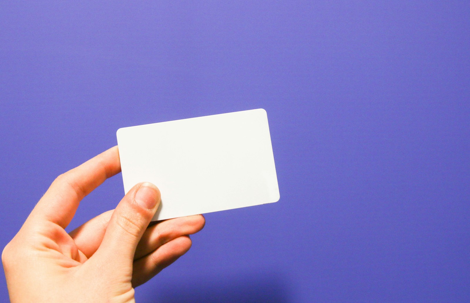 a hand holding a white business card against a purple background - AJ Bell ISA promotion offering a £100 Amazon Gift Card for new investors who deposit £10,000