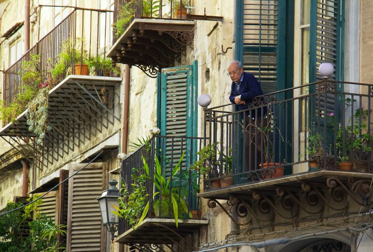 man in blue jacket standing on the balcony - A retiree enjoying time with friends, participating in social activities to avoid loneliness during retirement.