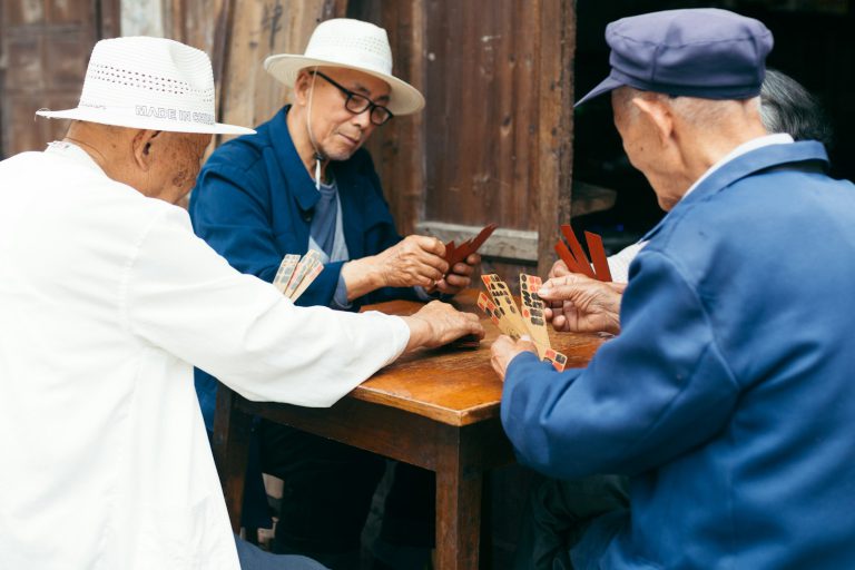 a group of elderly people playing a game of cards - A retiree meeting new friends through a community event, highlighting ways to build social connections after retirement