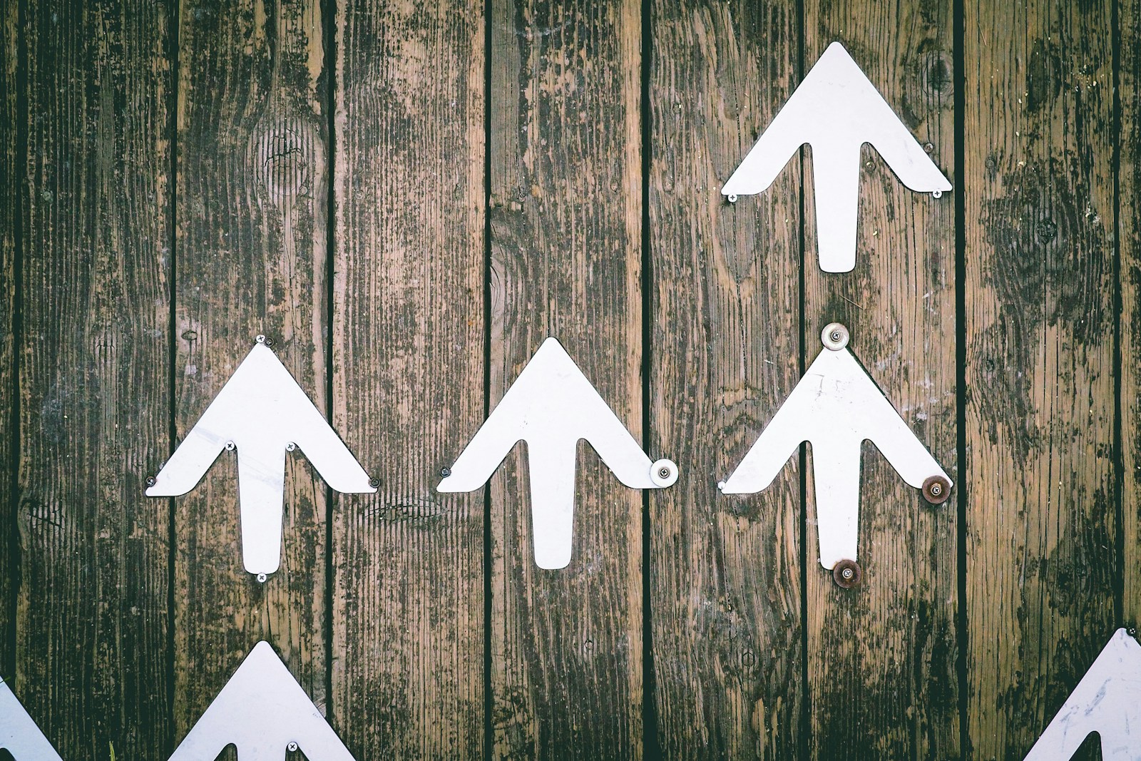 Several white arrows pointing upwards on a wooden wall - A retiree exploring options to increase retirement income and manage expenses effectively